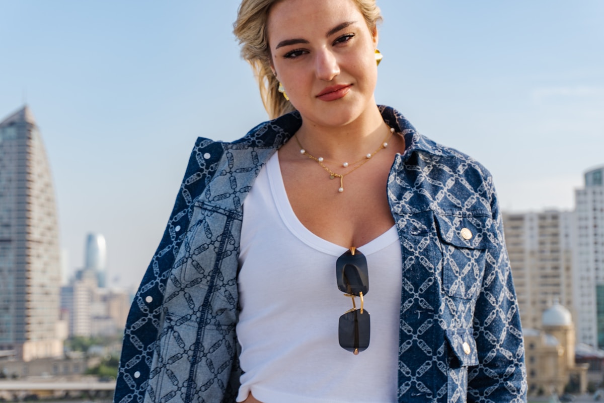 A young woman in a denim jacket with sunglasses.