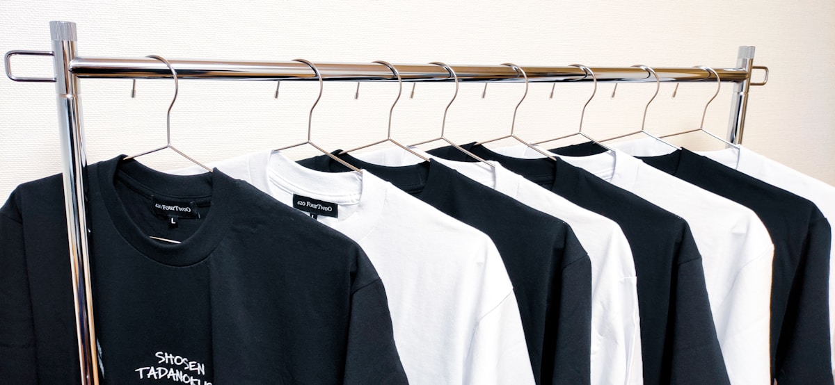 Rangée de t-shirts noirs et blancs sur un présentoir.