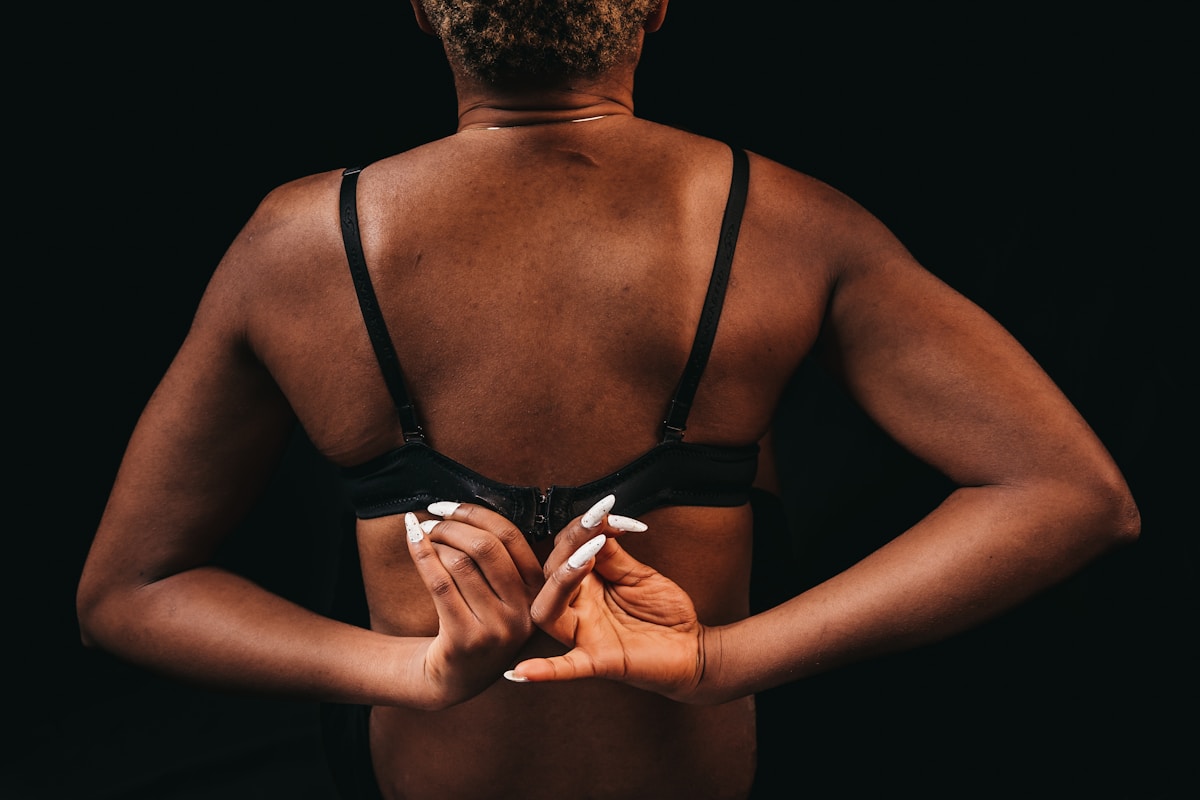 Dos d'une femme en sous-vêtements noirs, mains croisées.