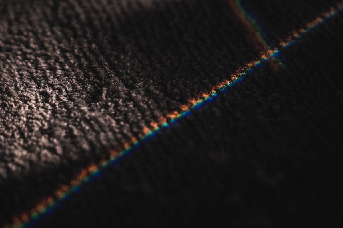 Texture de tissu sombre avec reflets irisés.