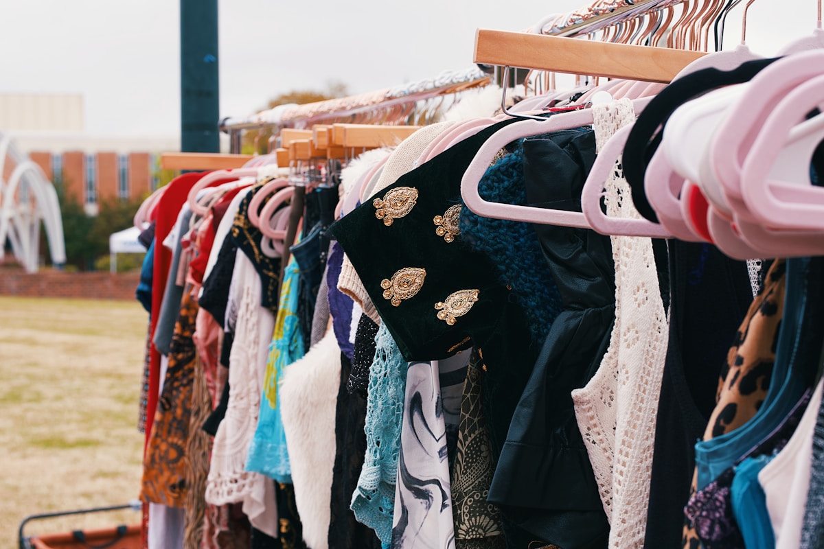 Vêtements colorés et ornés sur des cintres dans un marché aux puces.