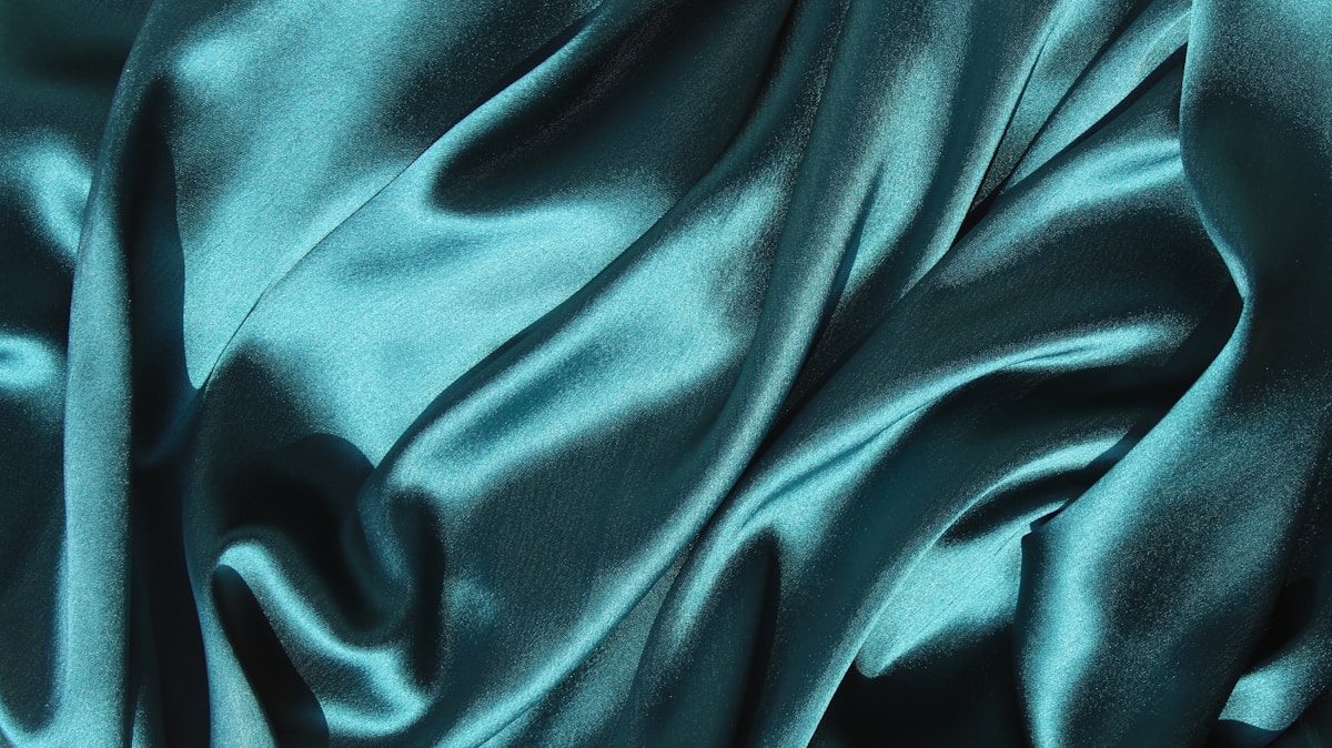 Tissu soyeux et ondulé aux nuances de bleu-vert profond.