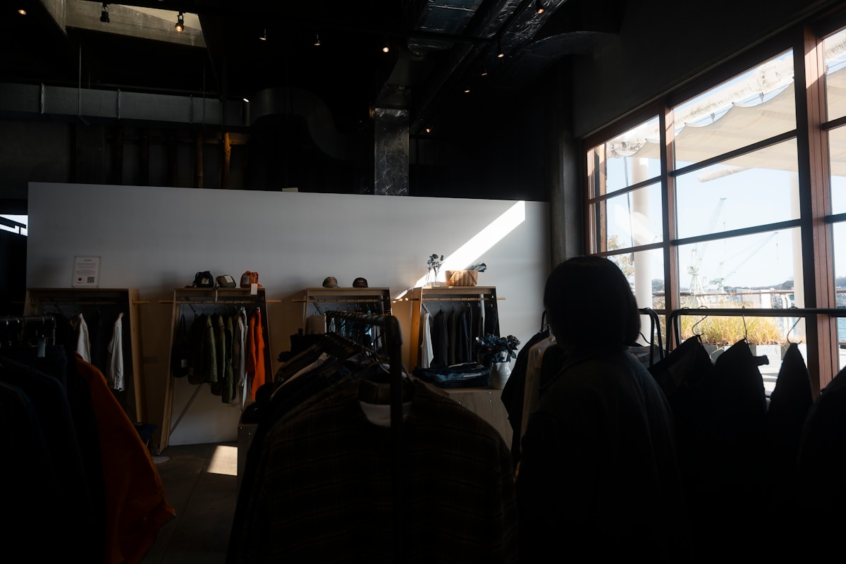 Intérieur sombre d'un magasin de vêtements avec des étagères et des vêtements.