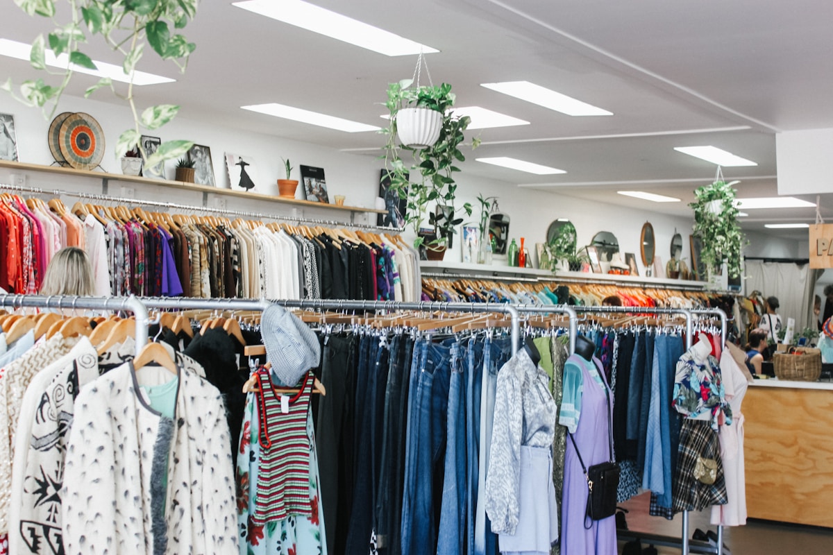 Boutique de vêtements colorés et éclectiques, avec des étagères et des cintres remplis de diverses tenues.