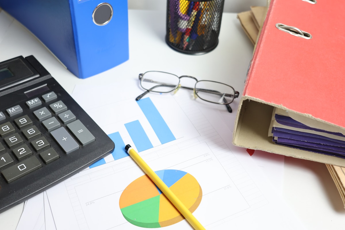 Bureau de travail avec calculatrice, graphiques, dossiers et lunettes.