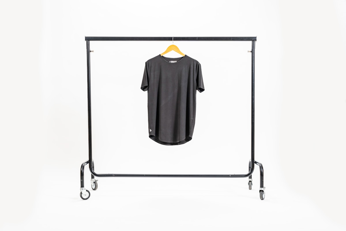 T-shirt gris suspendu sur un portant métallique.
