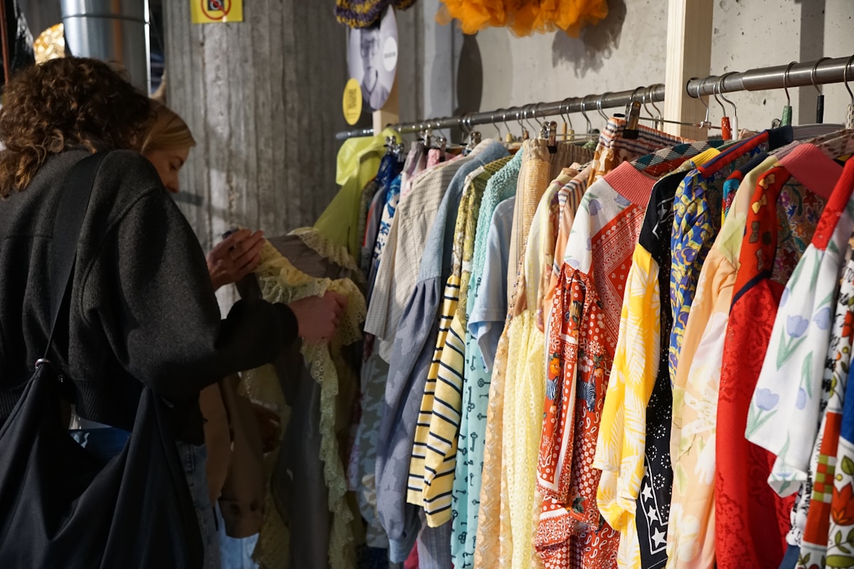 Vêtements colorés et variés suspendus sur des cintres dans un endroit encombré.