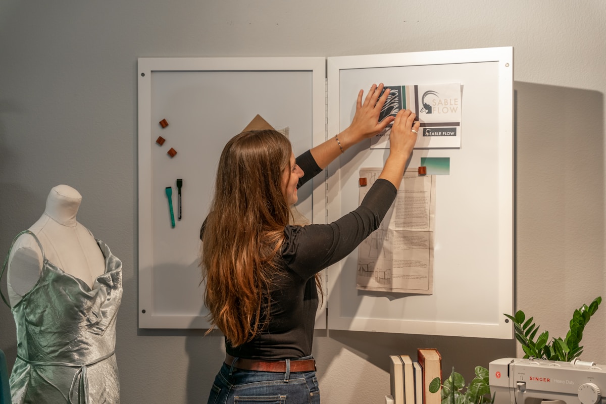 Femme arrangeant des affiches sur un tableau d'affichage dans un espace de travail.