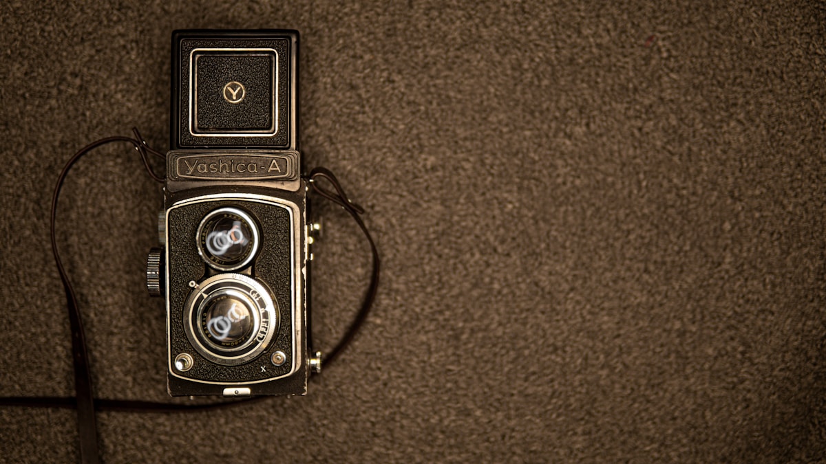 black and silver camera on brown textile