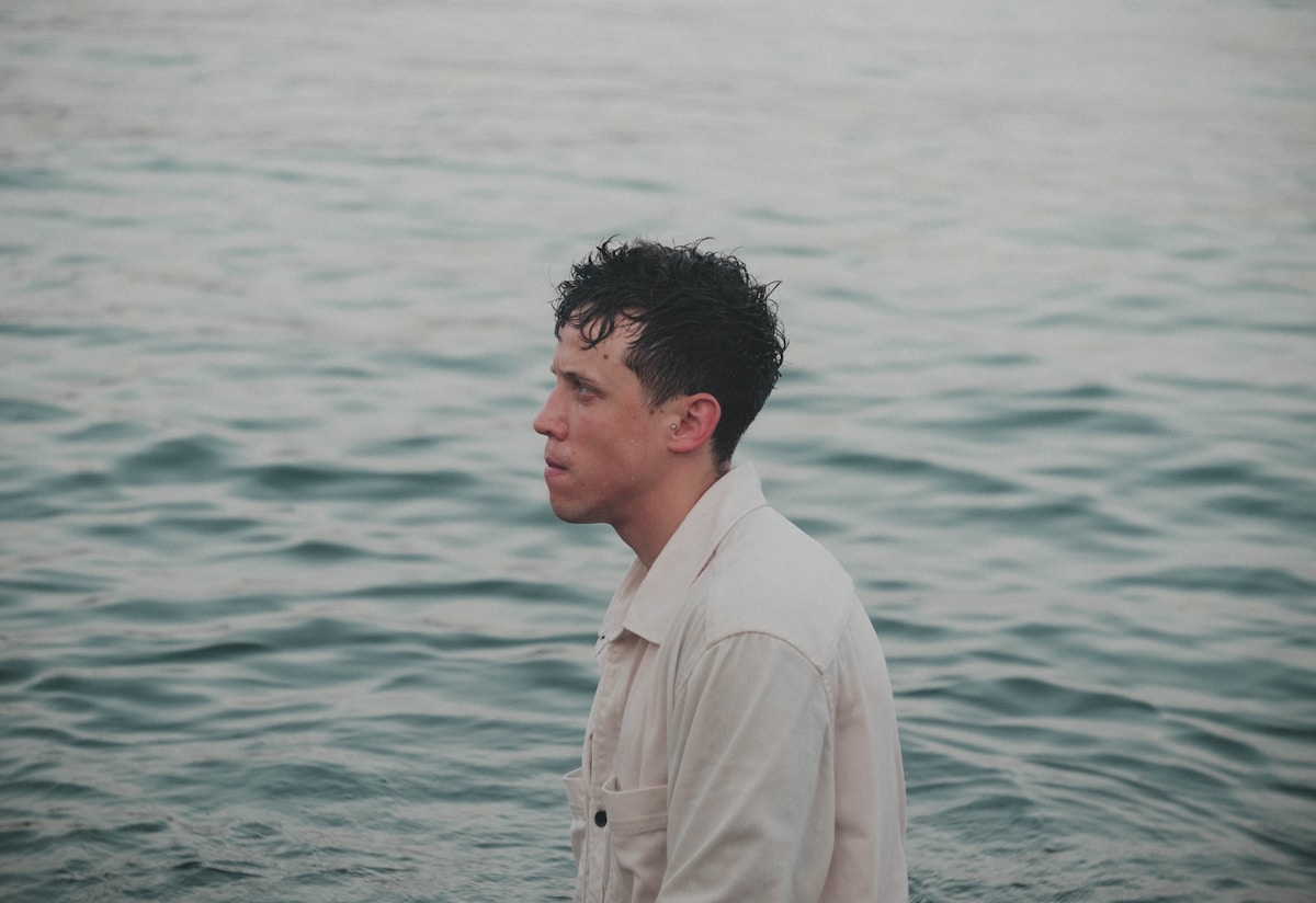 Homme pensif, debout dans l'eau, contemplant l'horizon.