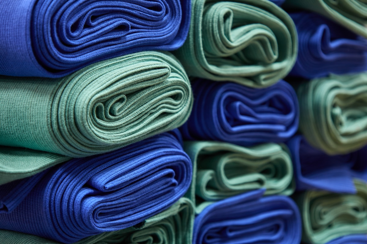 Rouleaux de tissus bleus et verts empilés.
