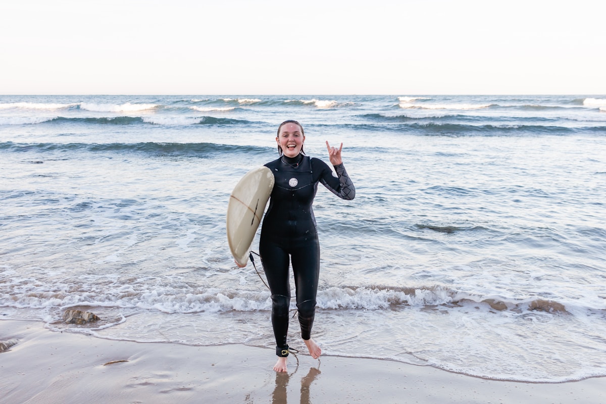 Surfeuse enthousiaste sur la plage avec une planche de surf.