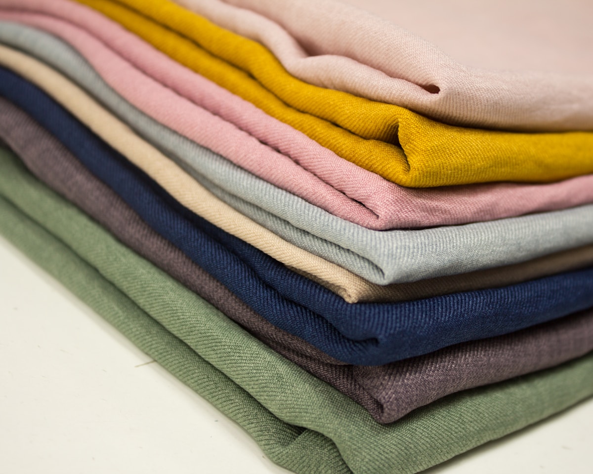 Pile de vêtements colorés en coton, textures douces et variées.
