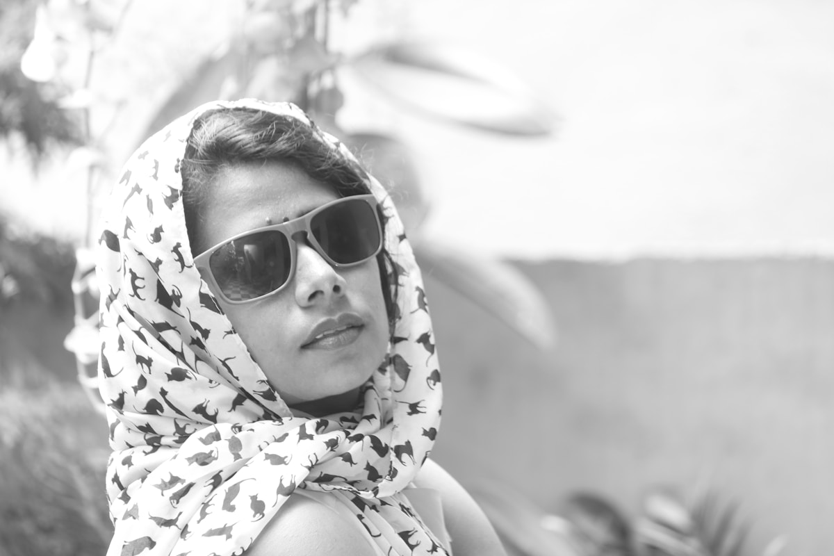 Femme portant un foulard à motifs et des lunettes de soleil.