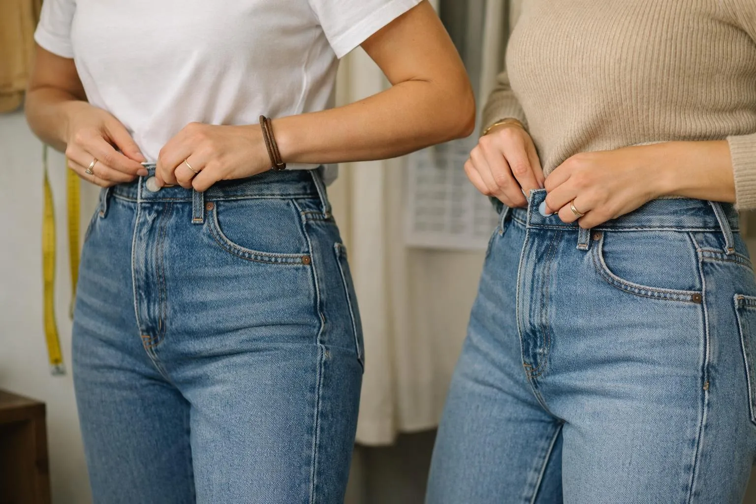 Mains de deux personnes ajustant leurs jeans en denim bleu.
