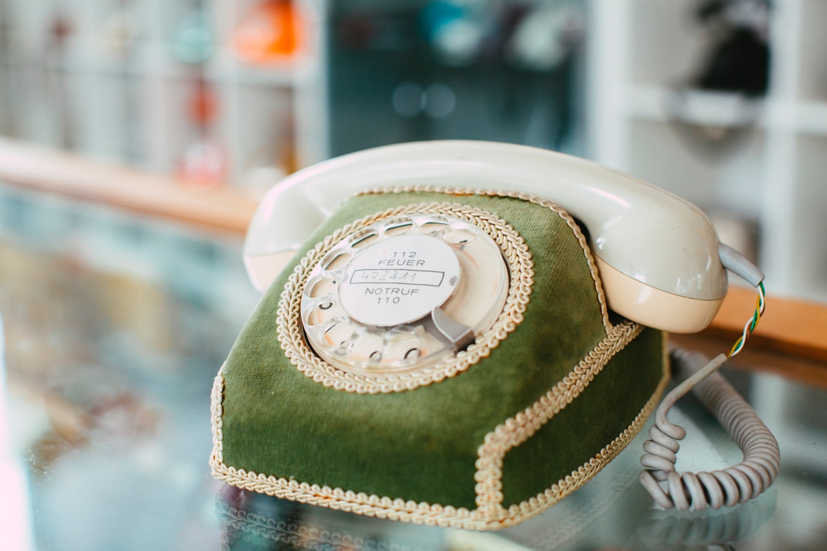 Téléphone vintage vert olive avec cadran rotatif et cordon.