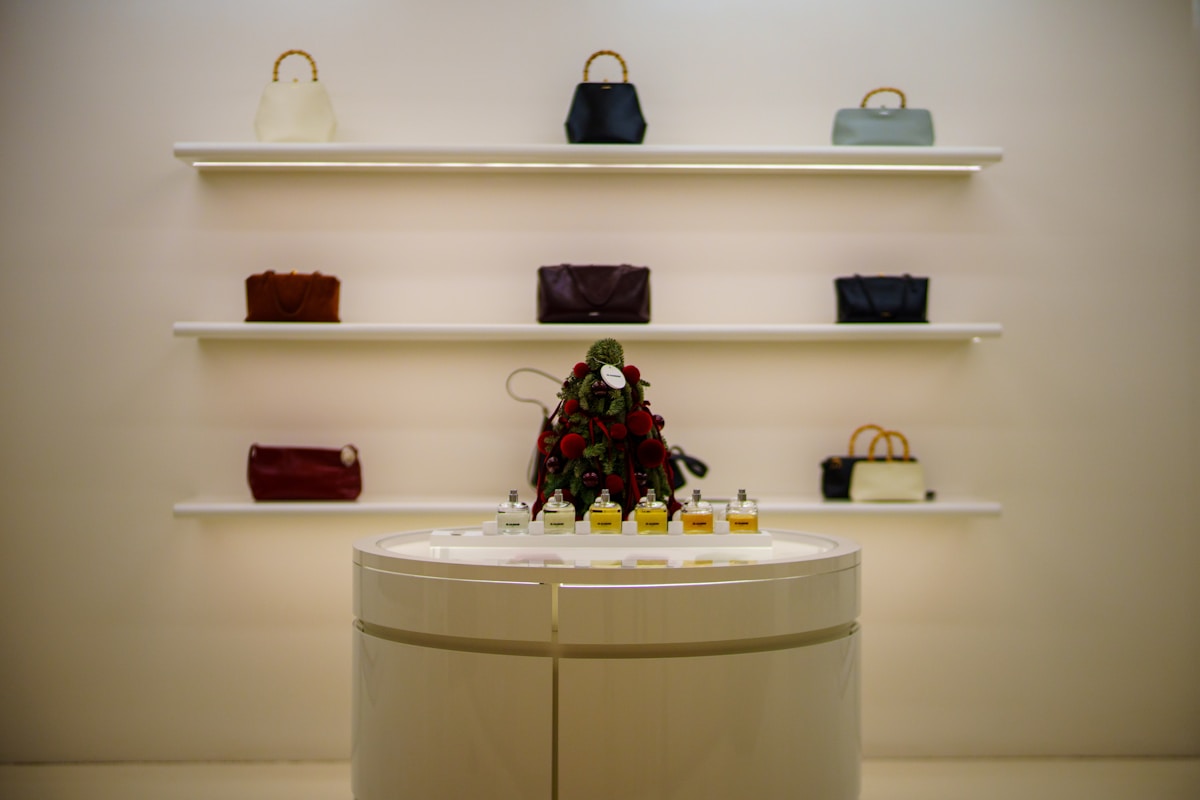 Étagères avec sacs à main, présentoir de parfums, décoration de Noël.