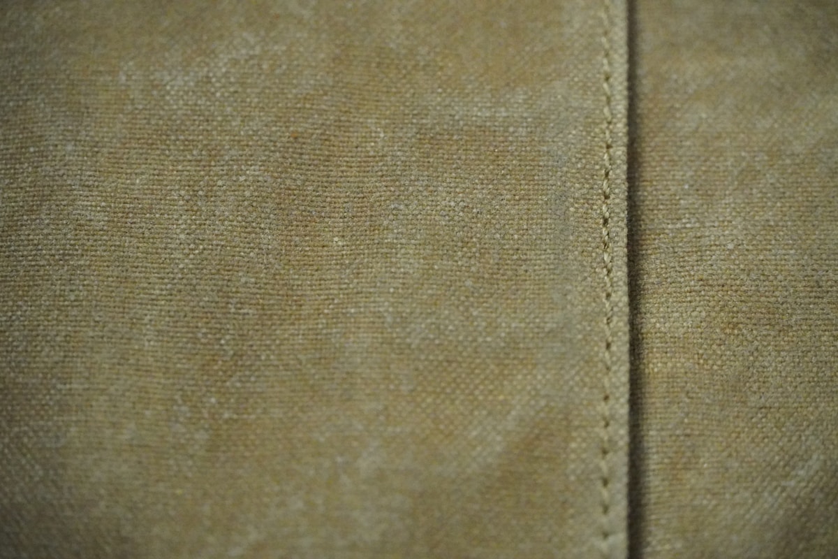 Texture de tissu beige avec couture apparente.