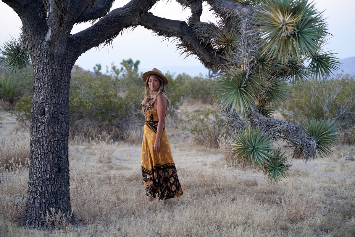 Femme dans un paysage désertique avec des arbres et des plantes.