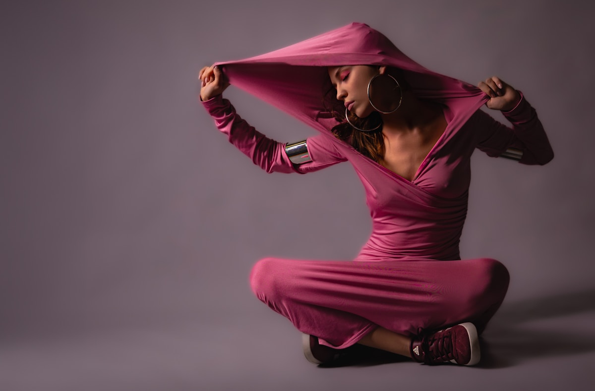 Femme en robe rose vif, posant avec élégance et dynamisme.