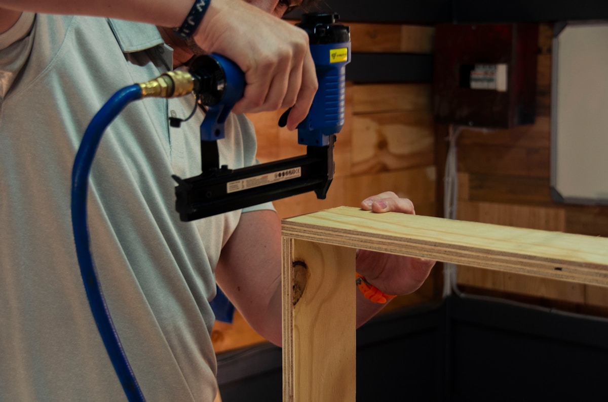 Un homme utilisant une perceuse électrique sur un morceau de bois.