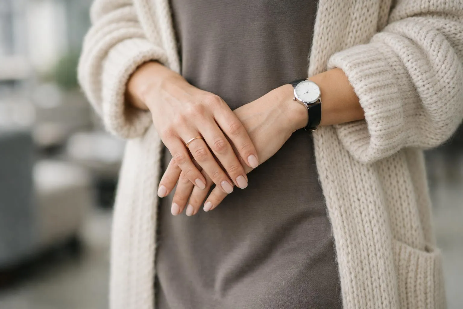 Mains croisées, montre-bracelet, bague, vêtements tricotés.