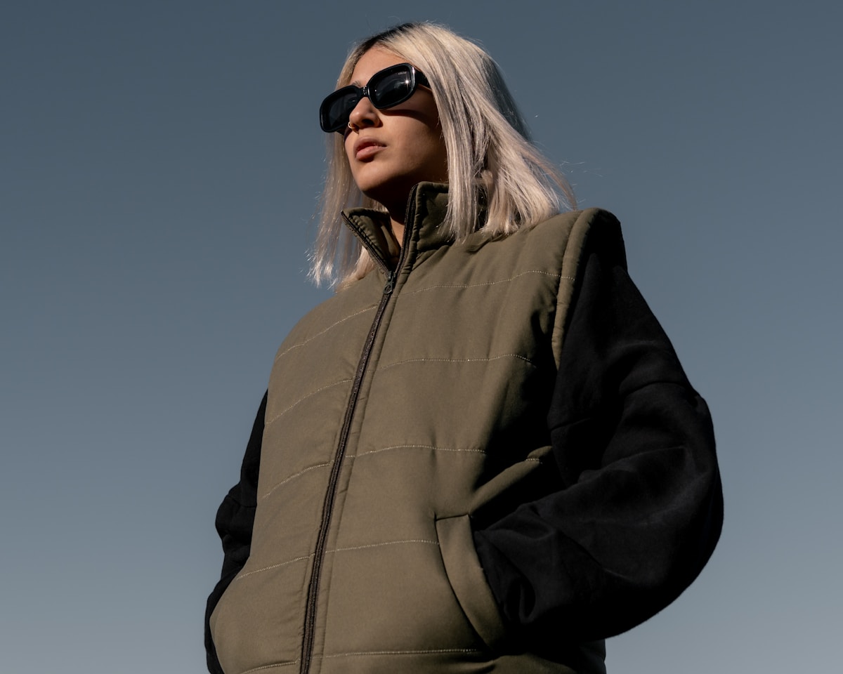 Femme portant un manteau matelassé et des lunettes de soleil.