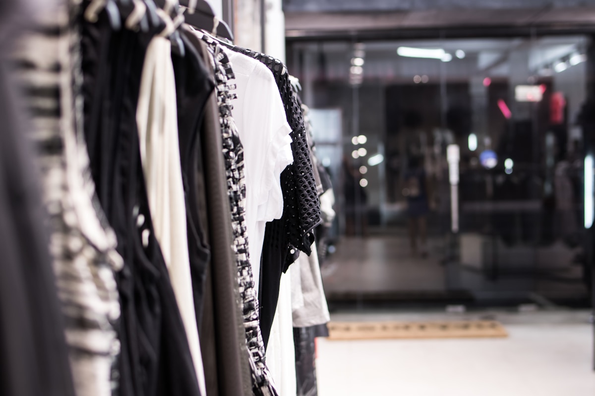 Vêtements noirs et blancs suspendus sur des cintres dans un magasin.