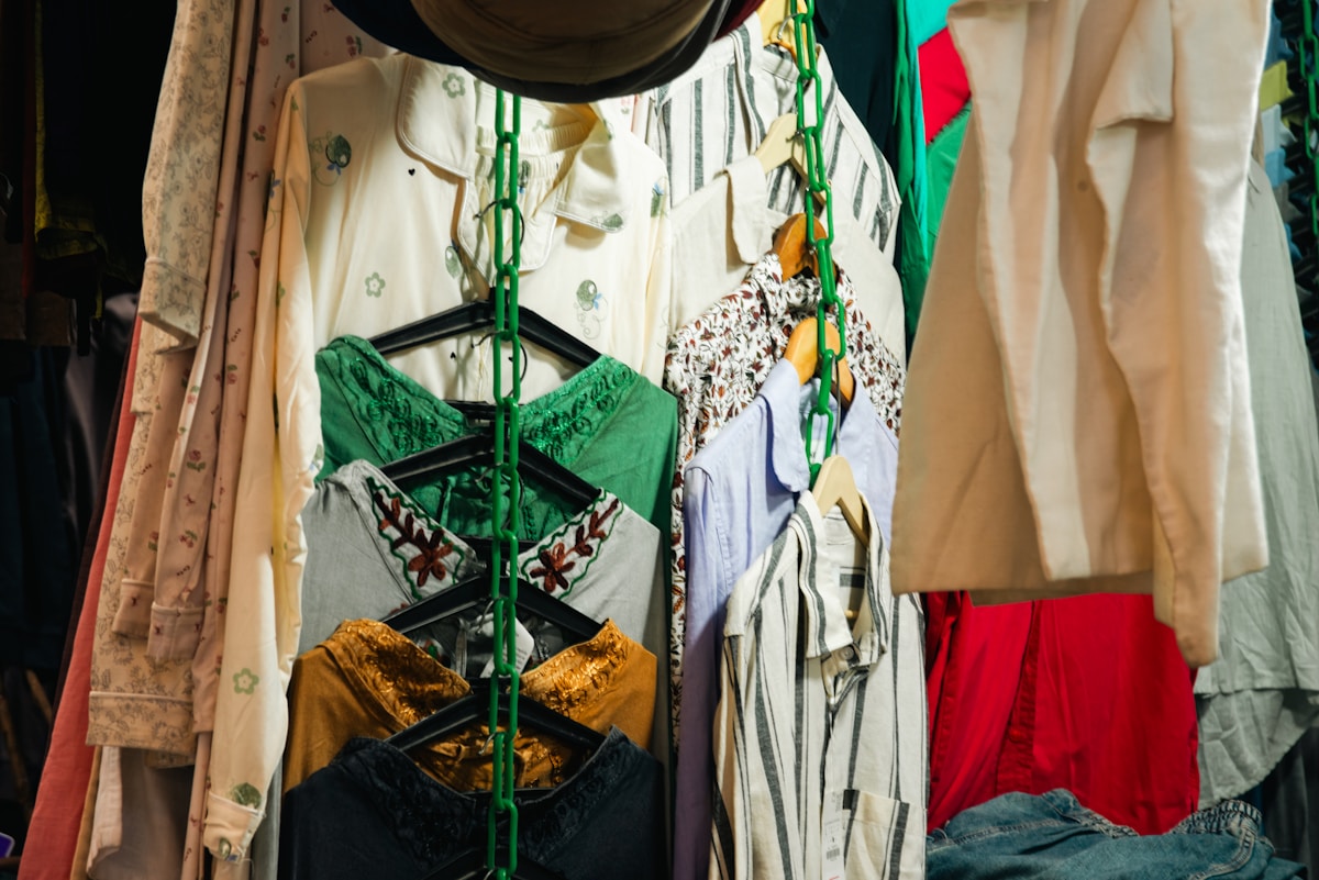 Vêtements colorés et ornés, présentés sur des cintres dans un magasin.