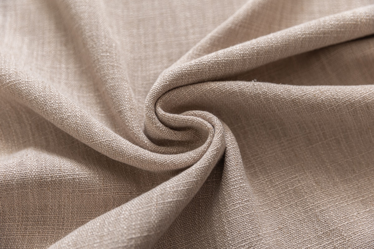 Texture de tissu beige froissé avec des plis élégants.