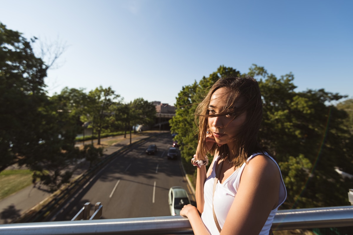 Jeune femme pensive sur un balcon avec vue sur la ville.