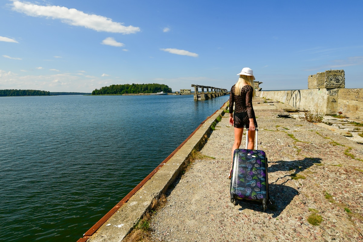 Femme avec valise sur un quai près d'un lac et d'un pont.