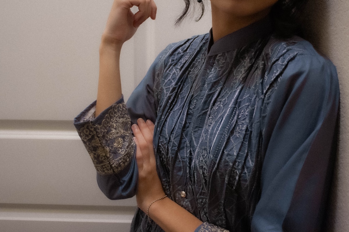 Vêtement bleu foncé texturé avec motifs dorés et détails élégants.