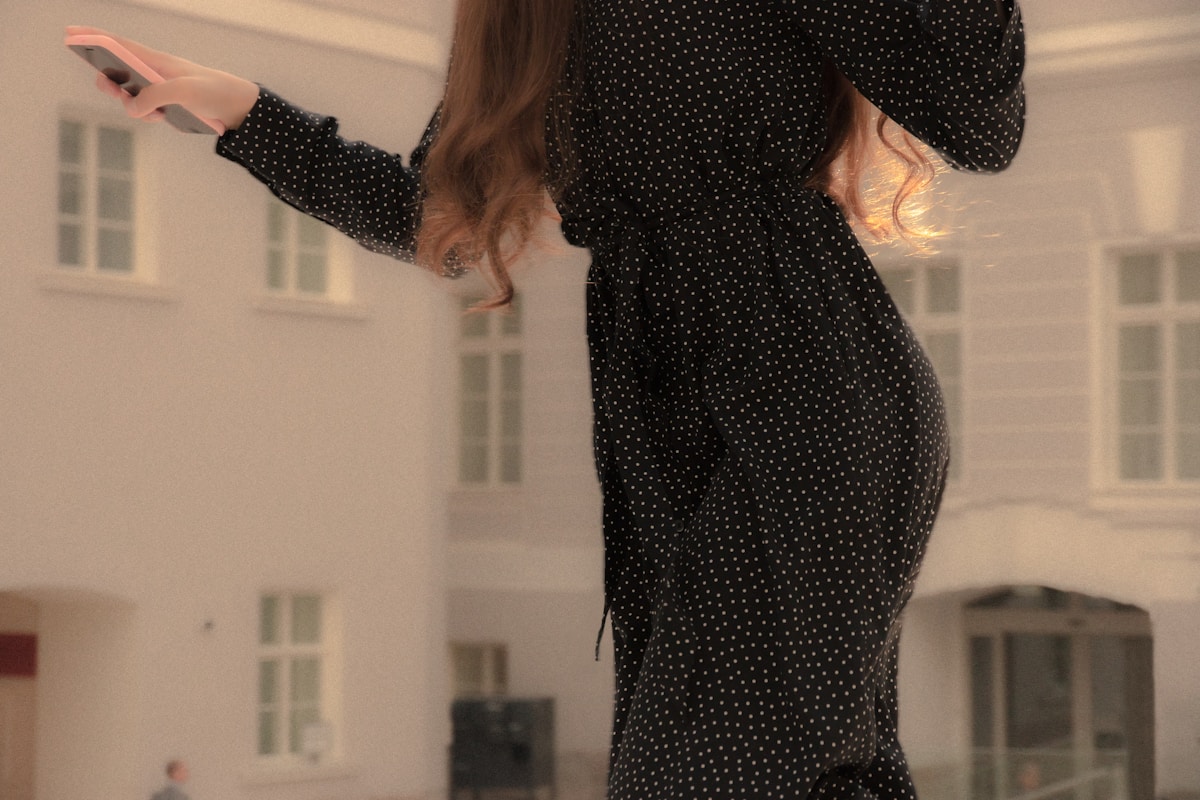 Femme portant une robe noire à pois blancs.