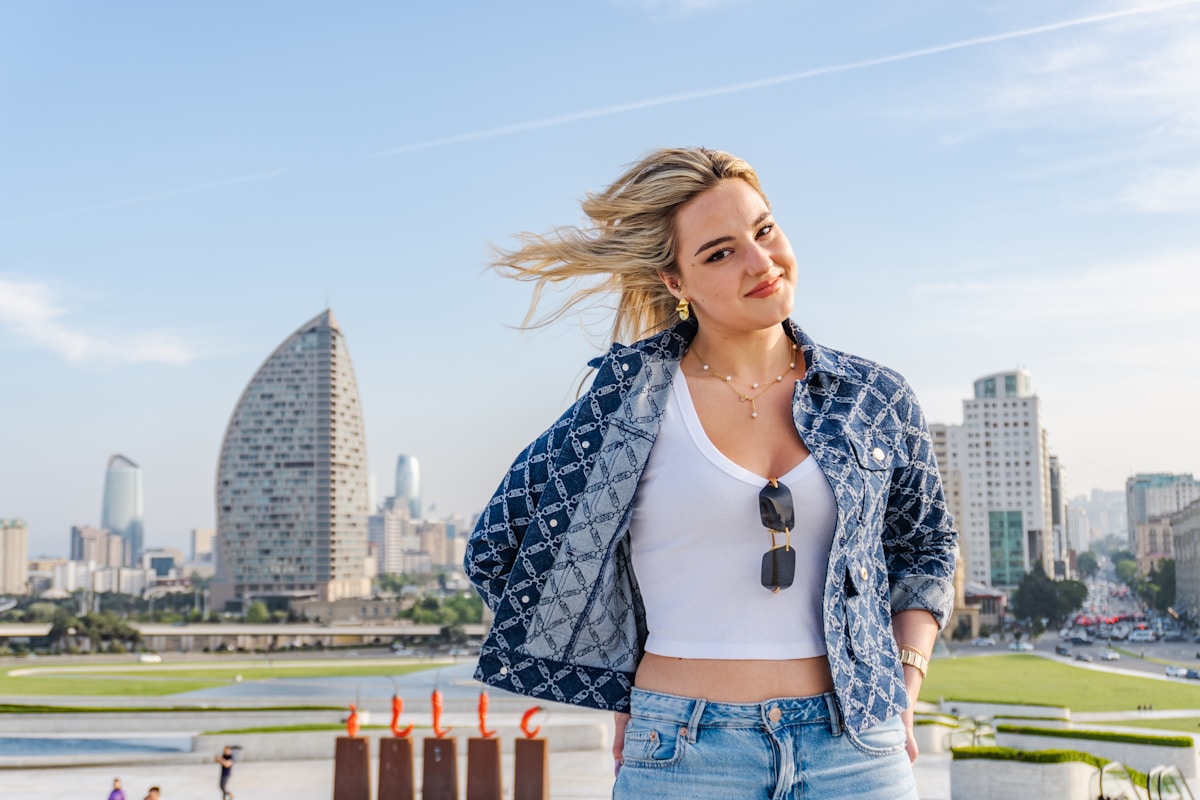 Femme blonde aux cheveux au vent devant un paysage urbain.