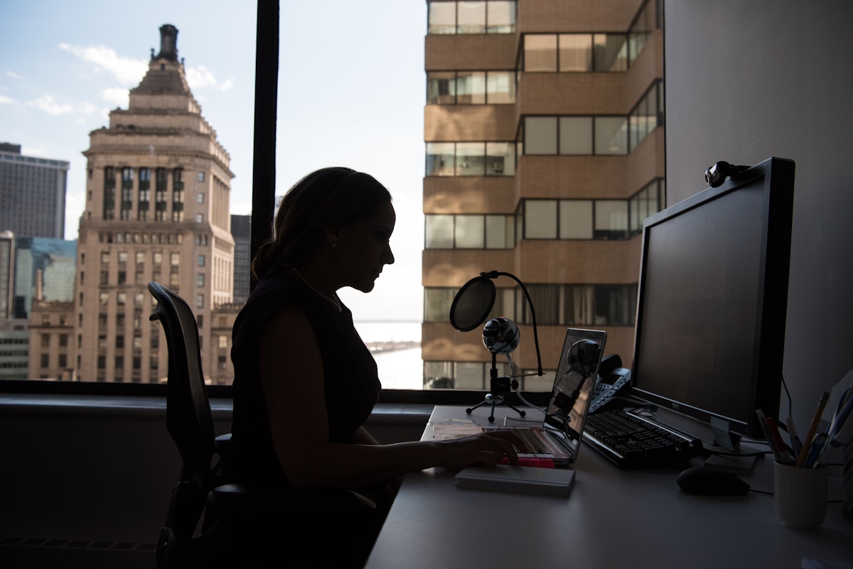 Silhouette d'une personne travaillant sur un ordinateur avec vue sur la ville.
