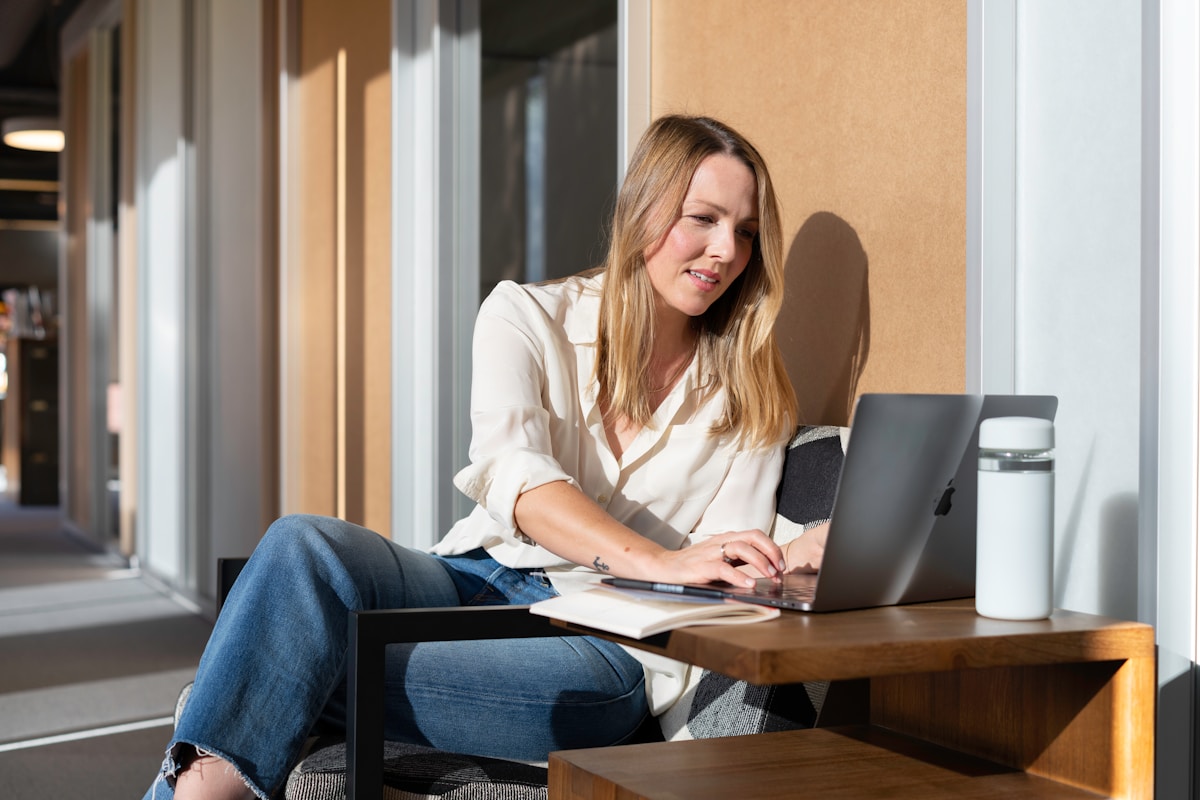 Femme assise à un bureau, travaillant sur un ordinateur portable.