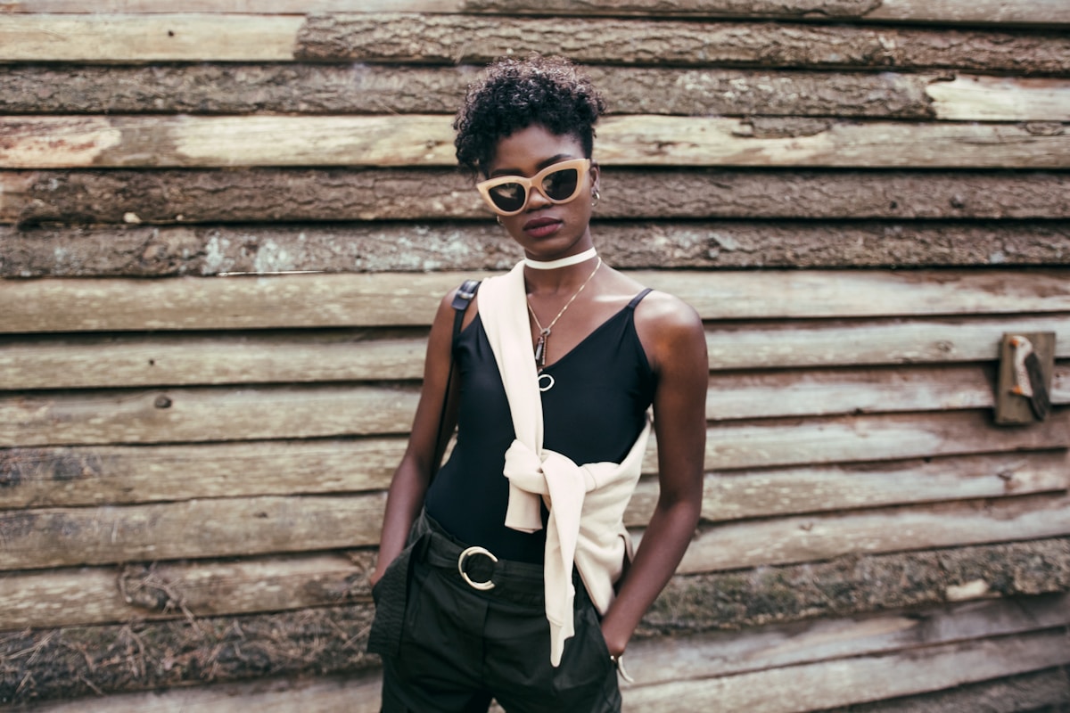 Femme afro-américaine élégante en tenue noire et lunettes de soleil.