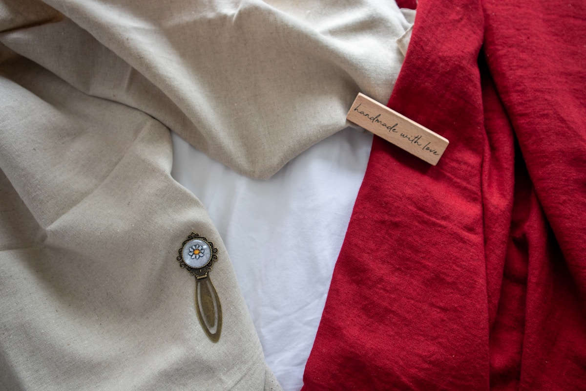 Tissu gris, serviette rouge, broche florale, étiquette "handmade with love".