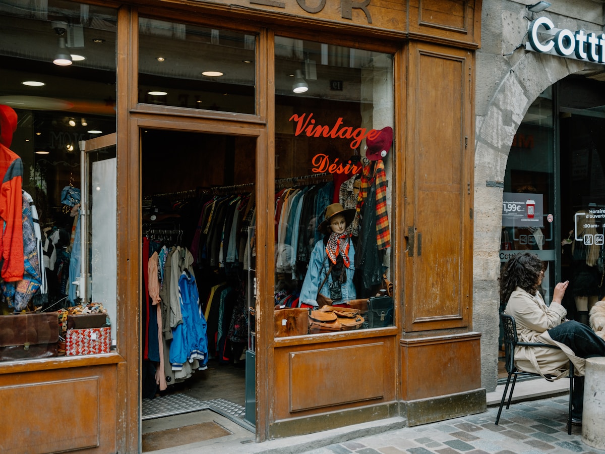 Vitrine d'un magasin vintage avec vêtements et accessoires colorés.