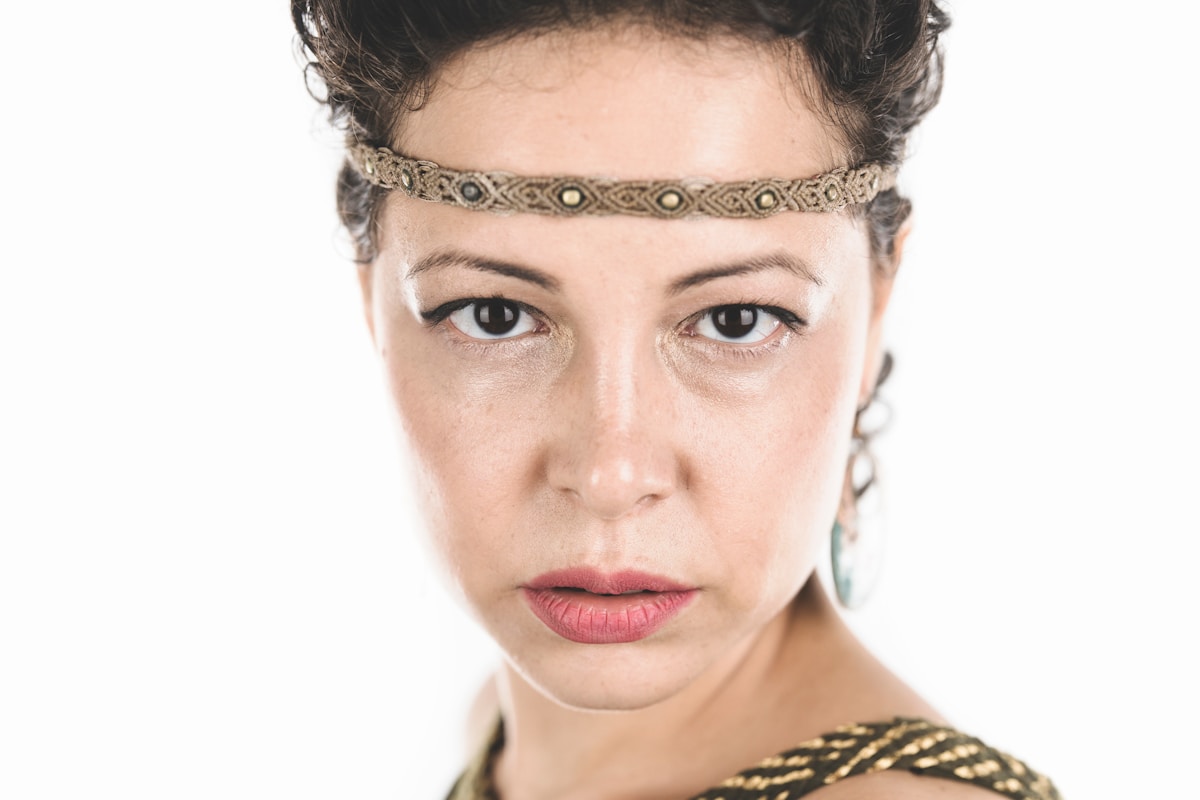 Femme au regard intense, portant un bandeau orné de motifs ethniques.