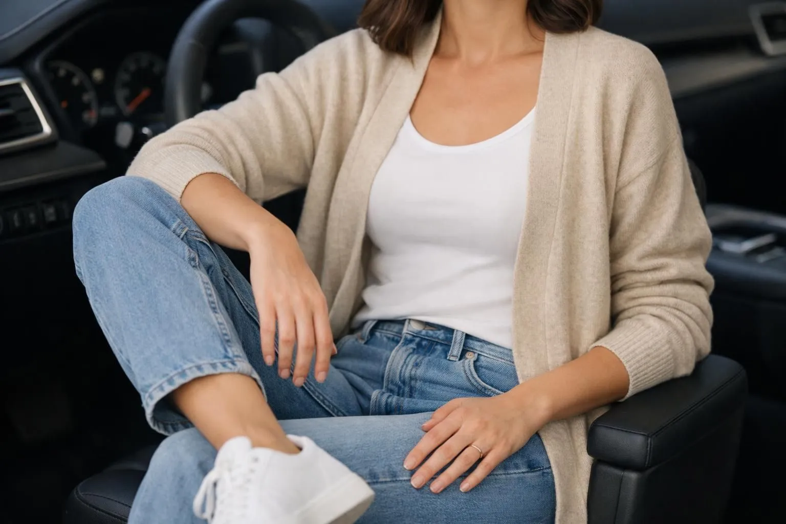 Woman wearing an open beige cardigan over white tank top with light denim jeans and white sneakers, casual California-inspired outfit styled for everyday wear, natural lighting, fashion photography, minimalist aesthetic