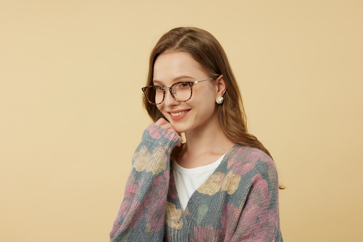 Jeune femme souriante portant des lunettes et un chandail coloré.