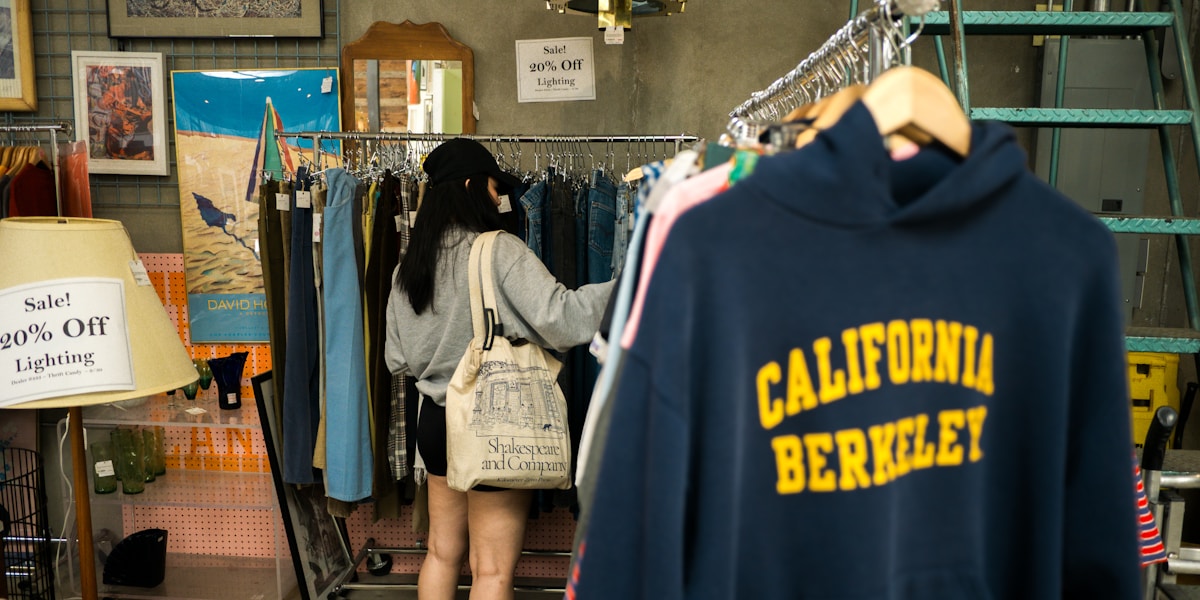 Boutique de vêtements avec affiches de soldes et vêtements sur des présentoirs.