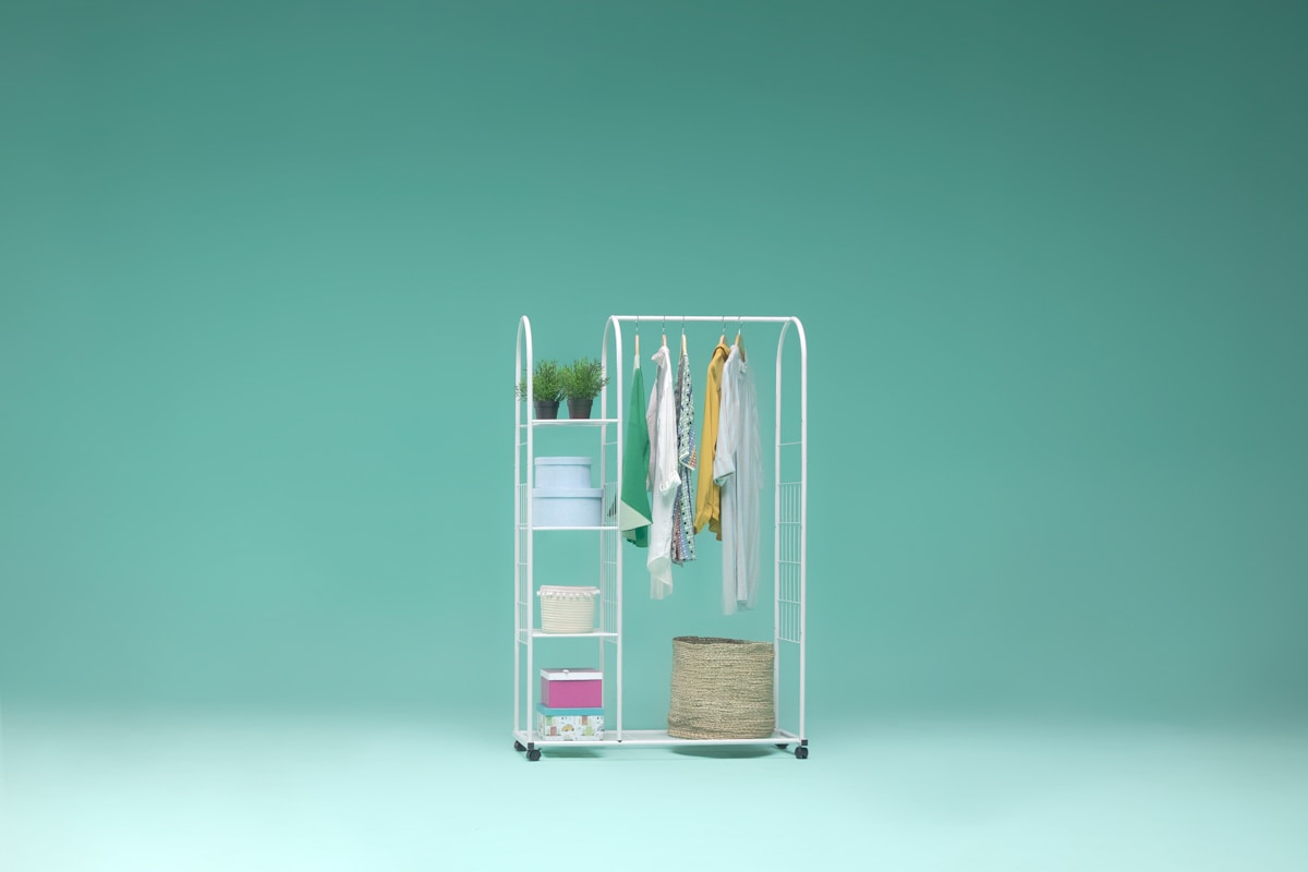 Étagère blanche avec vêtements et accessoires de rangement.