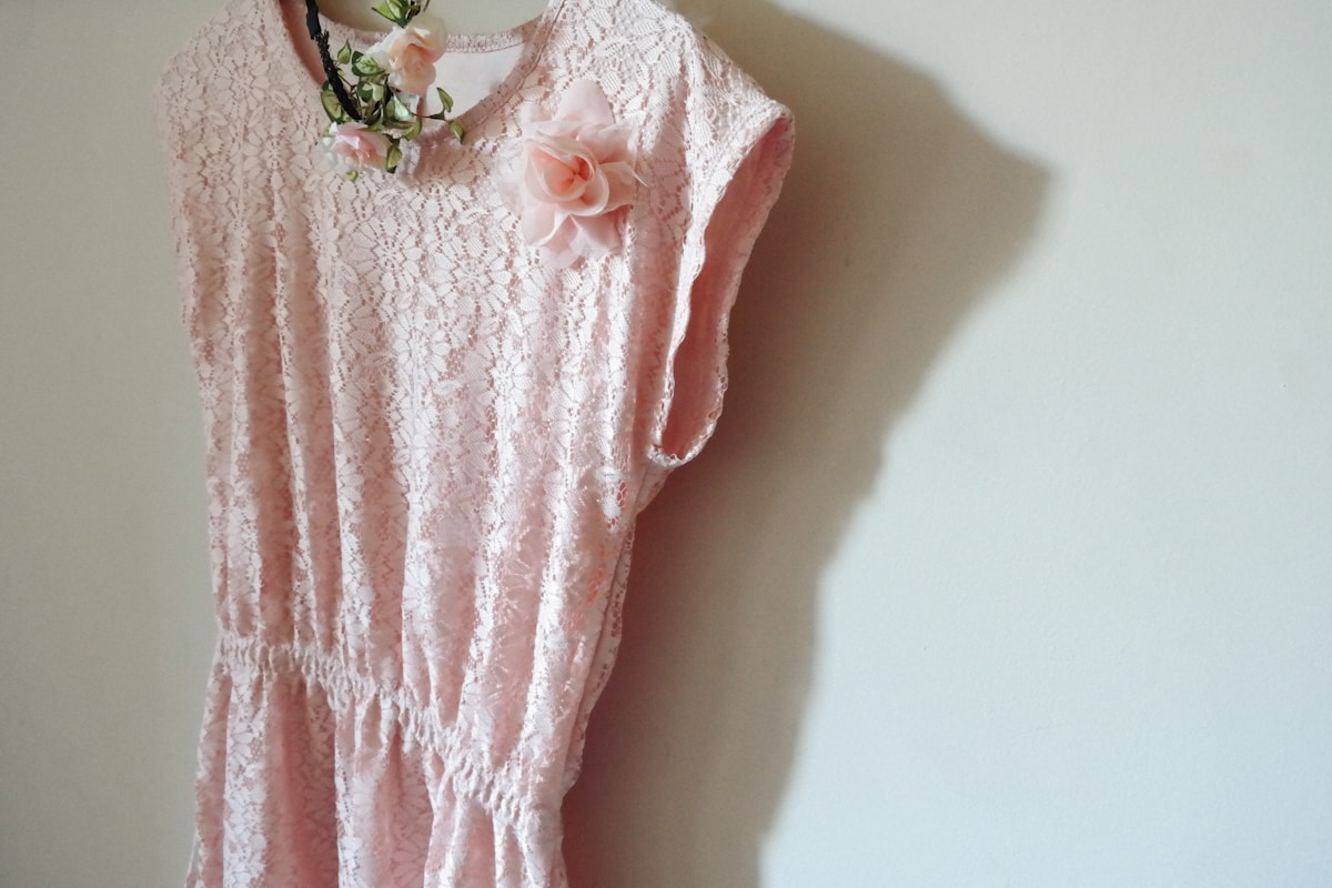 Robe rose pâle en dentelle avec fleurs décoratives.