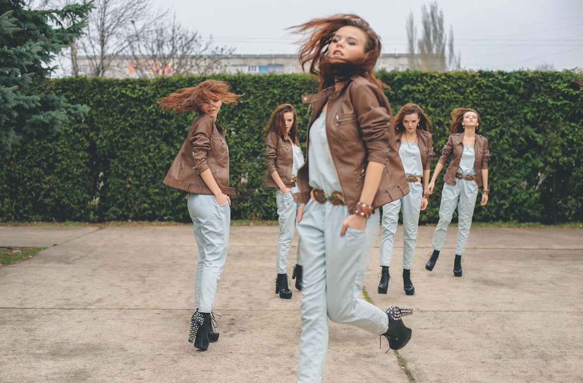 Groupe de femmes marchant dans un parc, vêtues de vestes en cuir et de jeans.