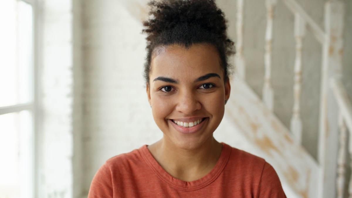 Jeune femme afro-américaine souriante avec des cheveux bouclés.
