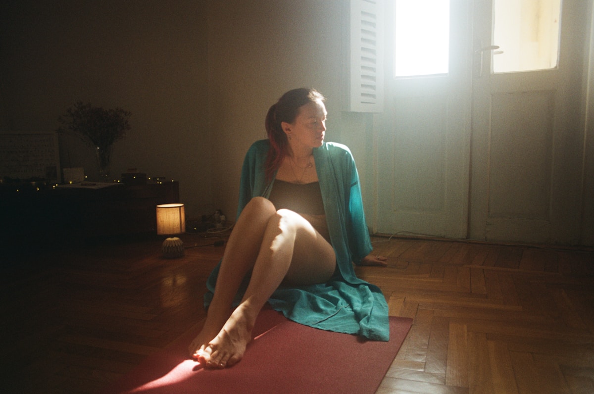 Une femme assise sur un tapis de yoga dans une pièce.