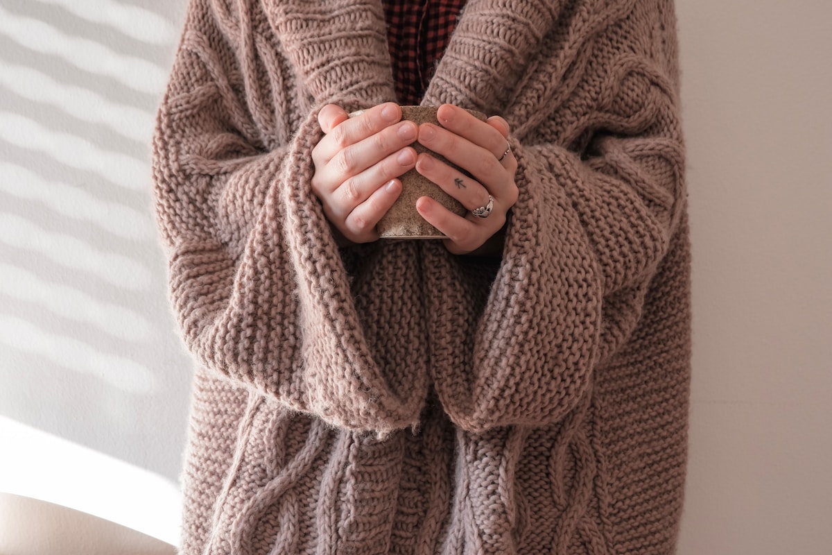 Mains croisées dans un pull en tricot rose.